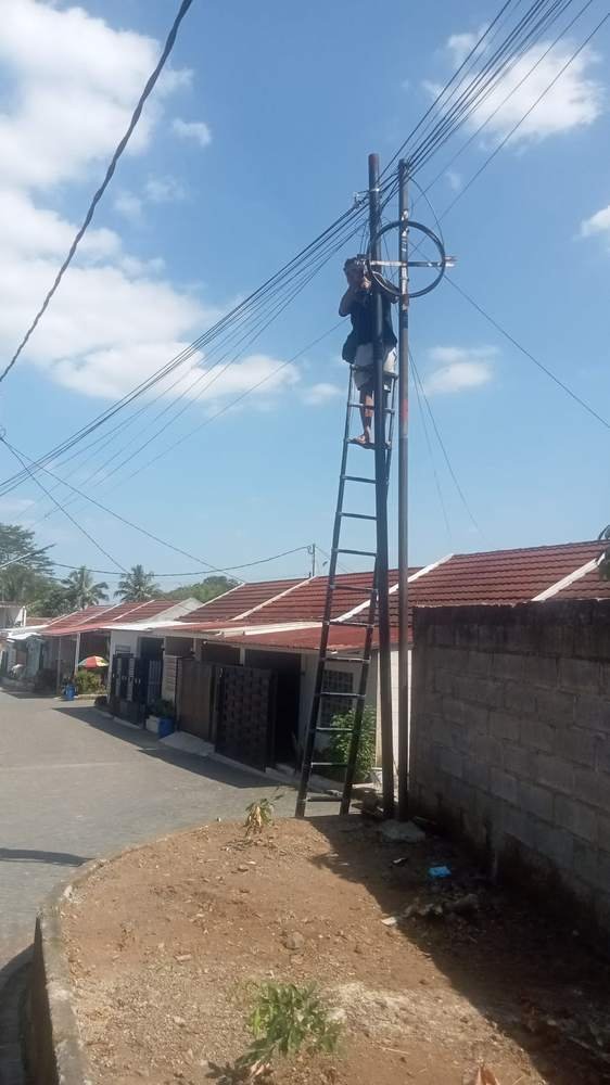 Teknisi memanjat tangga di tiang jaringan untuk perawatan kabel di permukiman